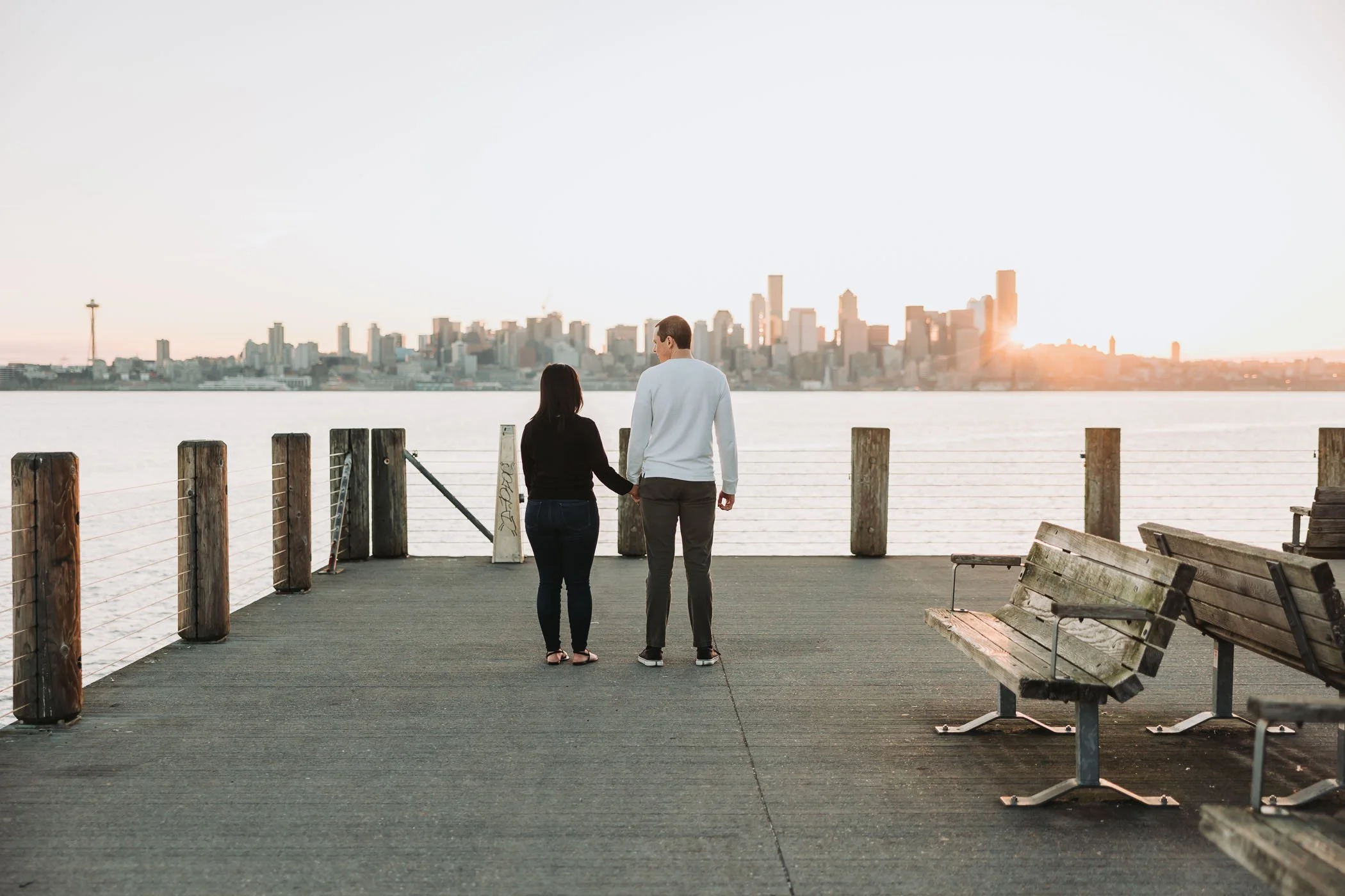Couple enjoys the sunrise on Alki Beach, overlooking the Seattle Skyline