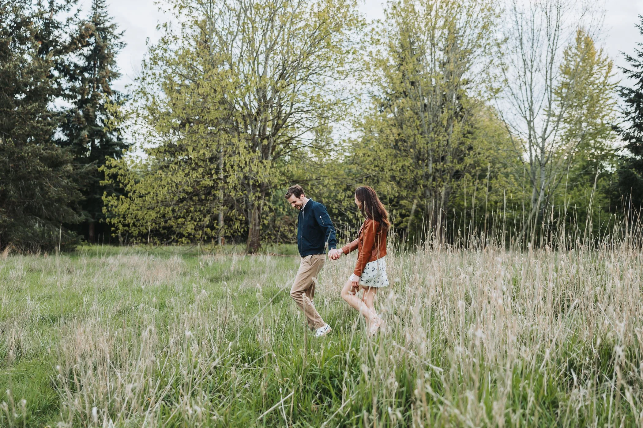 Couple runs through high grass at Discovery Park in Seattle, WA